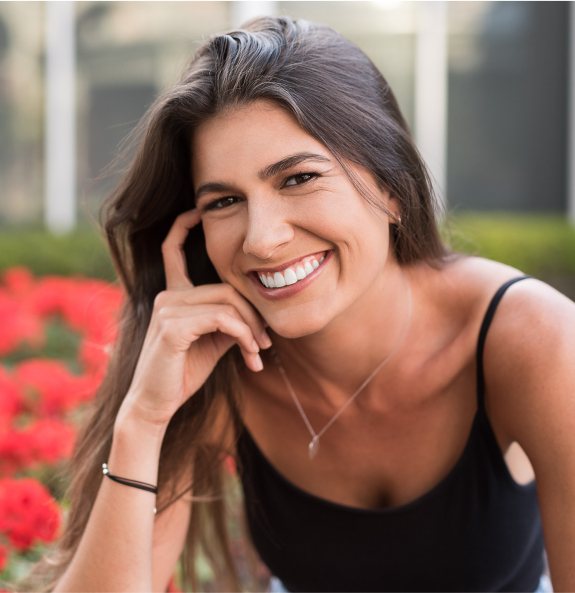 Woman smiling with flower bushes in background