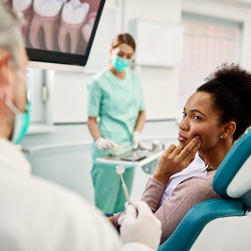 Woman with toothache talking to emergency dentist