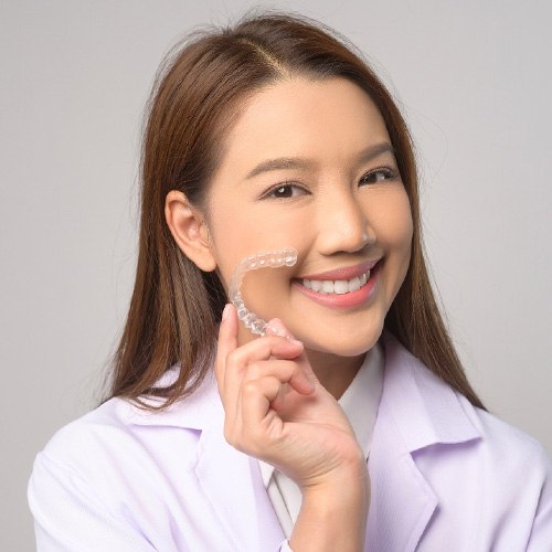 Smiling patient holding clear aligner