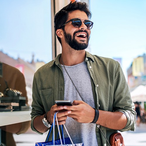 Man with sunglasses smiling while shopping outside