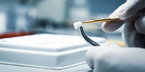 Gloved hands customizing a dental crown