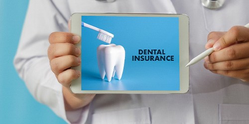 Dentist’s hands holding digital tablet displaying dental insurance