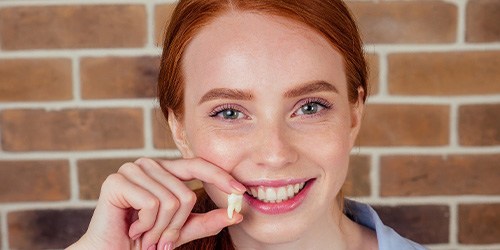 A woman holding an extracted tooth