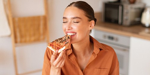 Woman enjoying meal in kitchen at home