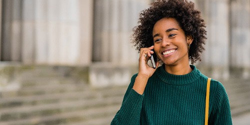 Woman smiling while talking on phone outside