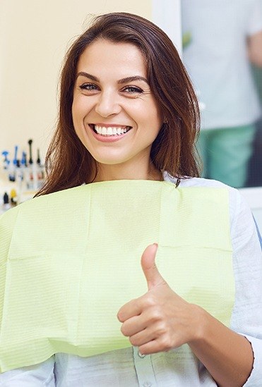 Smiling pattient giving a thumbs up in the dental office