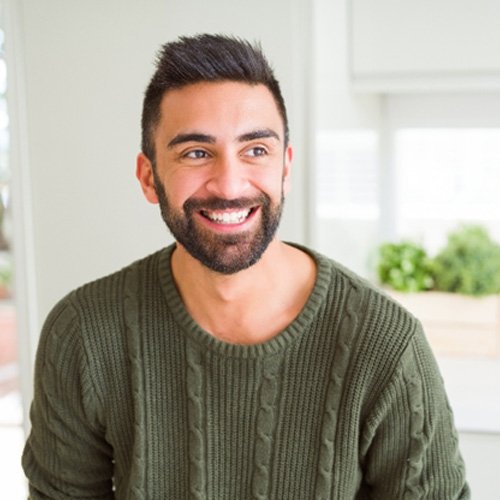 Man in green shirt smiling in kitchen