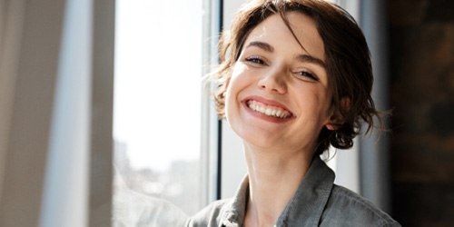 Woman standing by a window and smiling