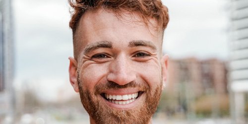 Bearded man smiling while standing outside in the city