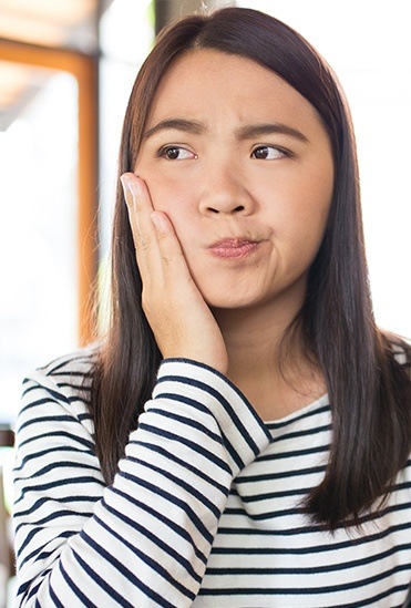 Woman in need of emergency dentistry holding cheek in pain