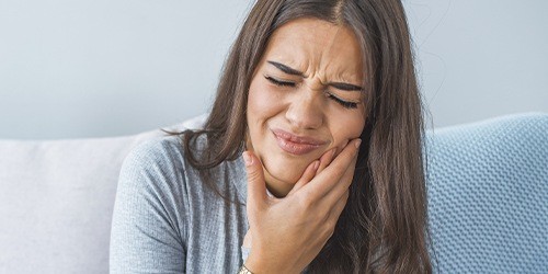 Woman with toothache holding cheek in pain