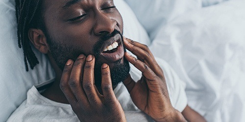 Man with jaw pain holding his cheeks