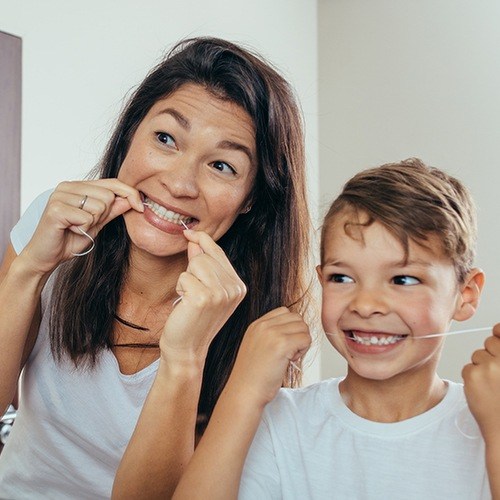 Mother and child flossing teeth to prevent dental emergencies