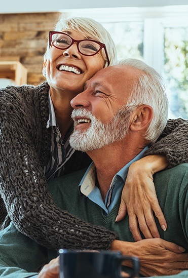 Man and woman smiling together after replacing missing teeth with dental implants