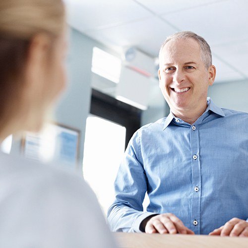 Man discussing the cost of dental implants with dental team member
