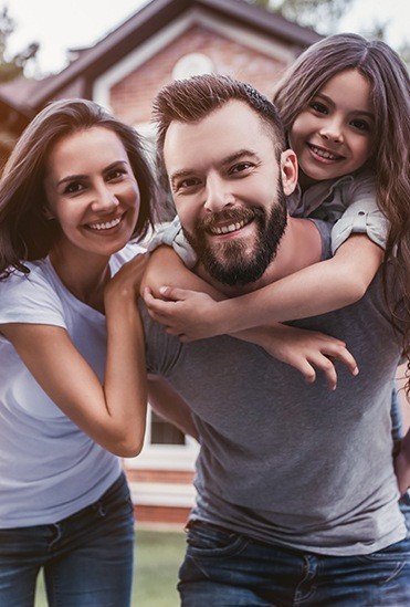 Parents and child smiling after visiting their dental insurance dentist