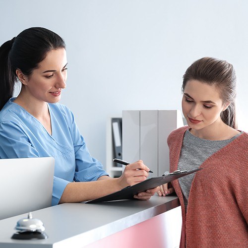 Dental team member and patient reviewing dental insurance forms