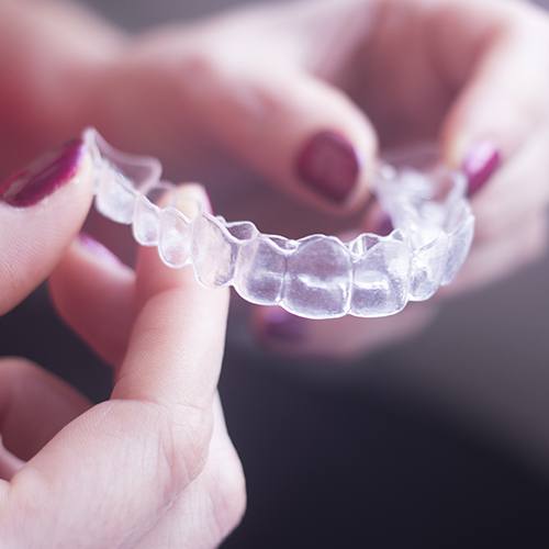 Hand holding an Invisalign tray