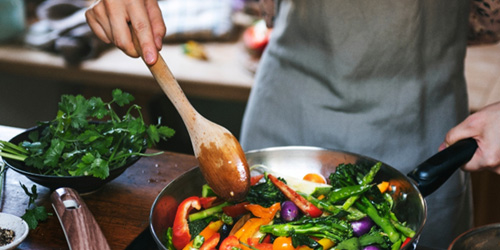 Chef in gray apron sautéing veggies