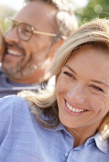 Man and woman with healthy smiles after replacing missing teeth