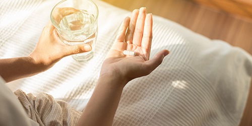 Woman holding a pill and water