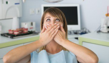 Woman in need of sedation dentistry covering her mouth in fear