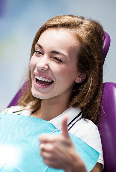 Woman in dental chair giving thumbs up