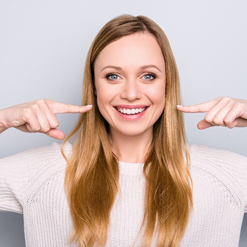 woman pointing to smile after getting veneers in Flower Mound