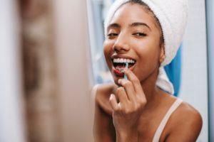 Woman flossing teeth in mirror