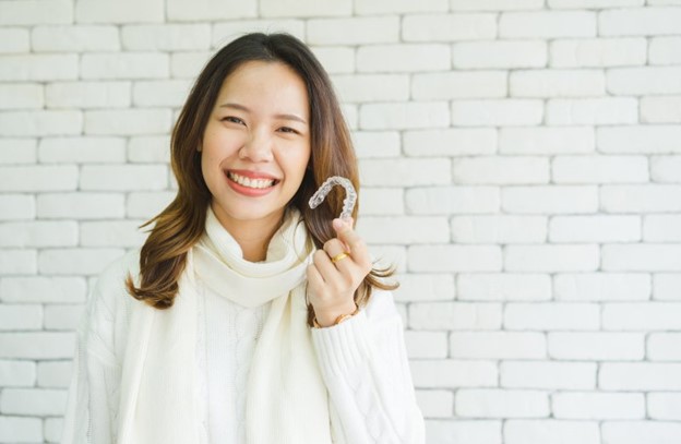 Woman holding her Invisalign clear aligner.