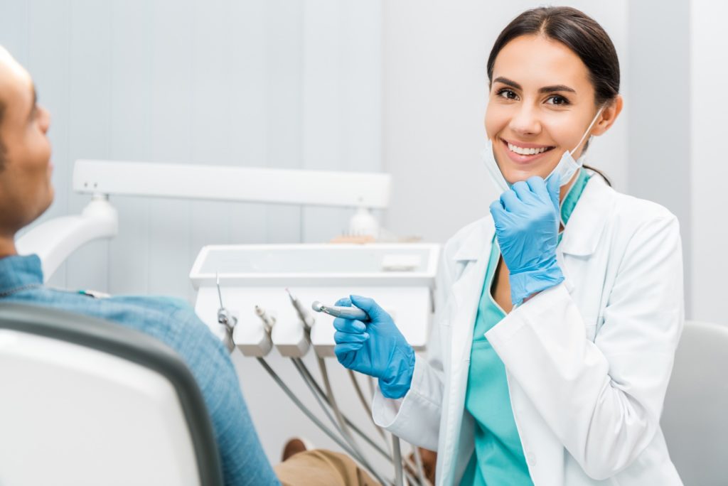 Female dentist smiling while sitting next to patient in treatment chair